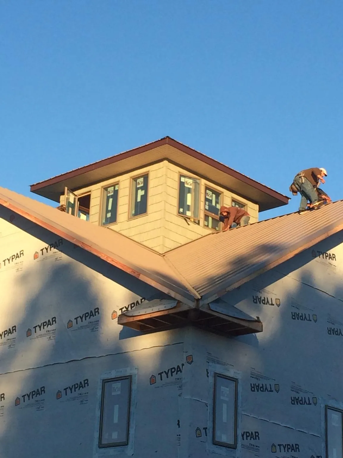Roofers working around a rooftop cupola on a new metal roof at sunset — Roof Waterproofing in Dover by Roofing Brothers